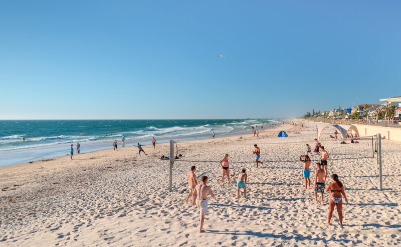 Orang-orang bermain bola voli di Pantai Henley pada hari yang cerah dan hangat.